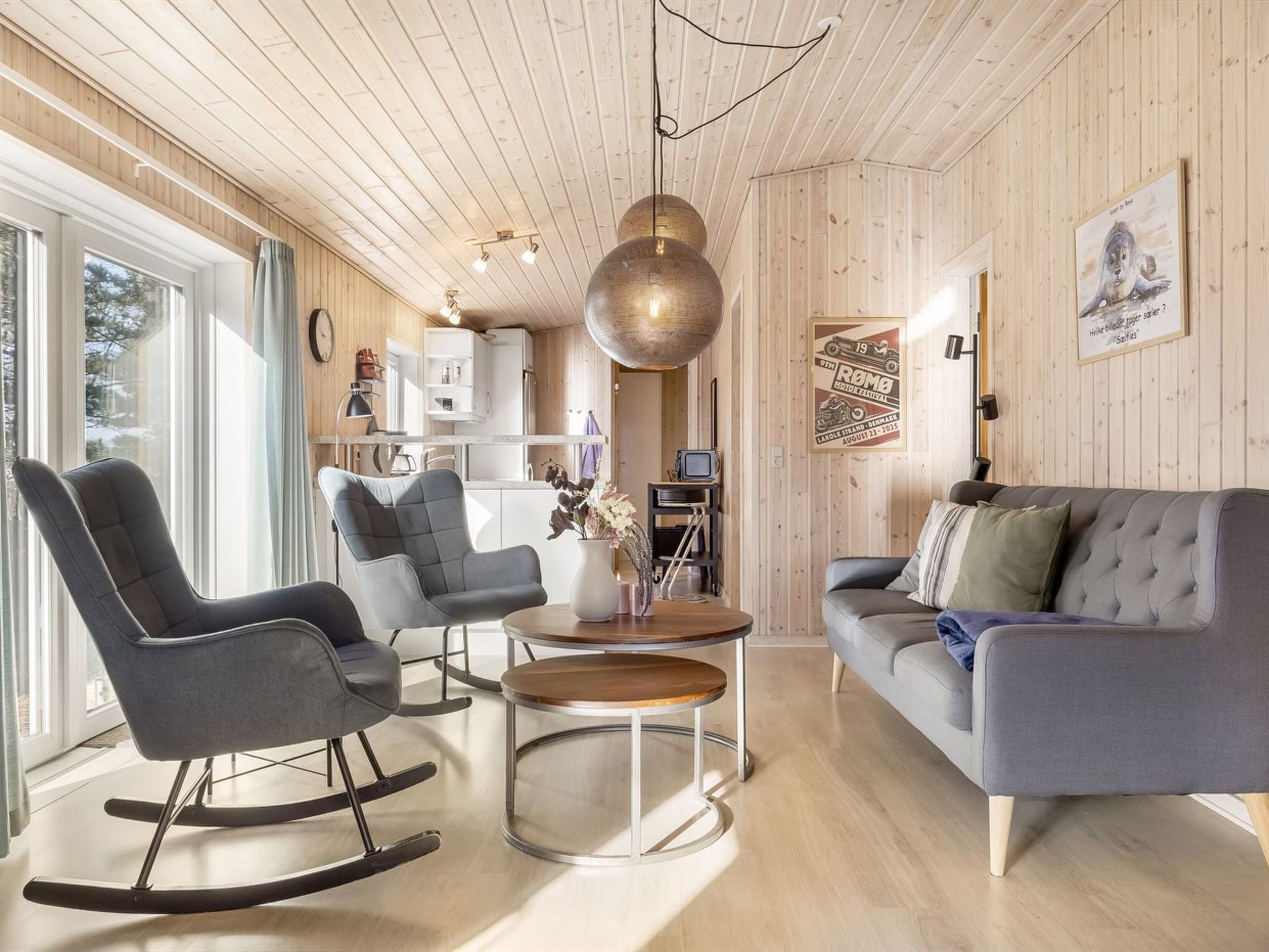 A modern living room with a grey sofa, a rocking chair, and a coffee table.
