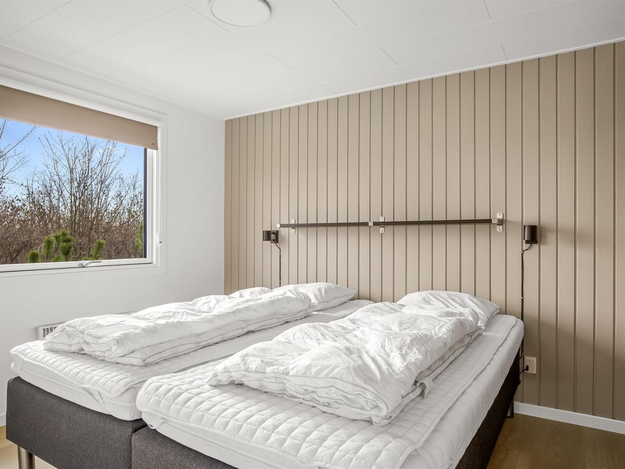 Une chambre à coucher avec un lit, une fenêtre et une étagère fixée au mur.