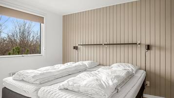 Une chambre à coucher avec un lit, une fenêtre et une étagère fixée au mur.
