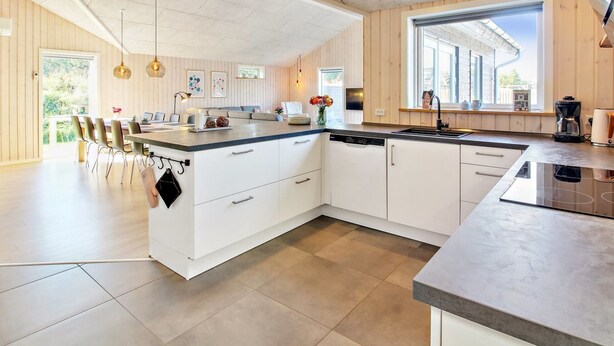 A modern kitchen with a large island, white cabinetry, and a view to the outside.