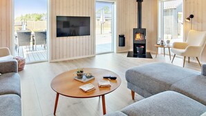 A modern living room with a large TV, a fireplace, and comfortable seating.