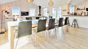A modern kitchen with a dining area, wooden floors, and pendant lighting.