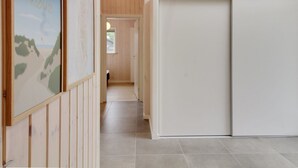 A hallway with wooden paneling, a framed picture on the left, and a sliding door on the right.