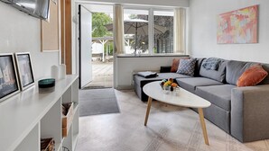 Una sala de estar moderna con un sofá gris, una mesa de centro blanca y un ventanal grande.
