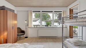 Un dormitorio pequeño con literas, cama individual, armario, escritorio y ventana con vistas al exterior.