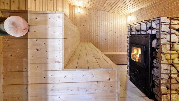 Una sauna de madera con chimenea de piedra y un banco.