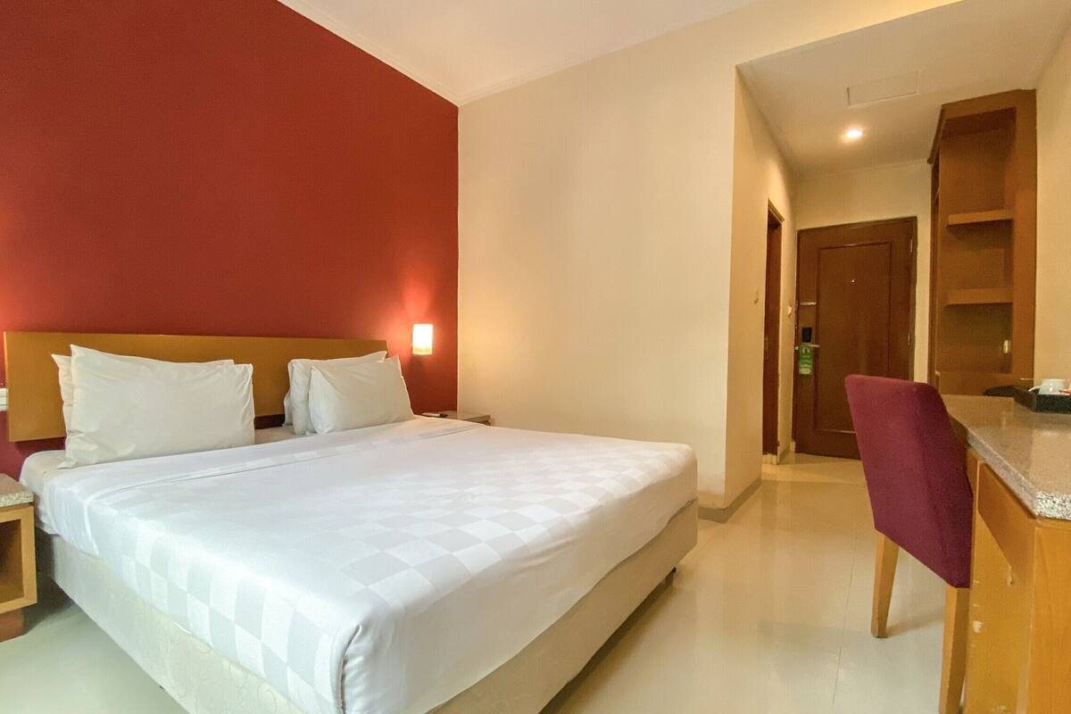 Une chambre d’hôtel avec un grand lit, des tables de chevet, un bureau avec une chaise et une kitchenette.