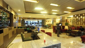 A hotel lobby with a reception desk, seating area, and a view of the street. - Lorin Dwangsa Solo Hotel (Surakarta)