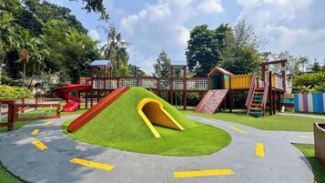Un parque infantil con toboganes, zonas de escalada y una zona de juego vallada.