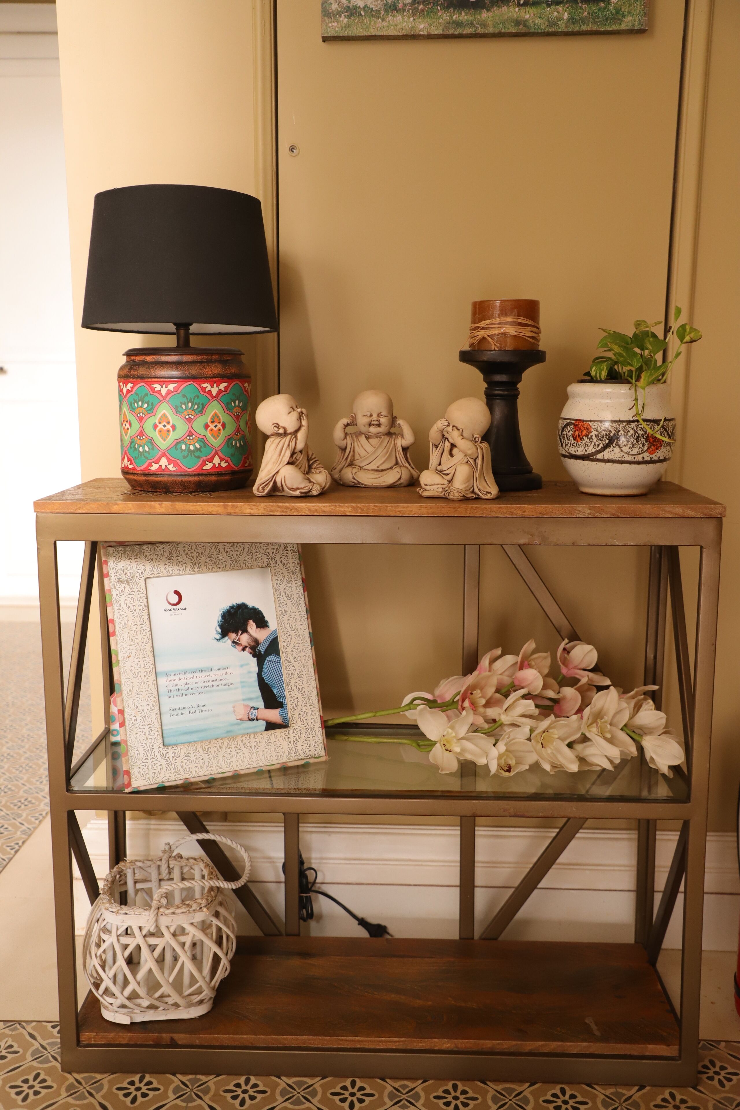 A wooden console table with a black lamp, decorative items, a framed photo, and a basket.
