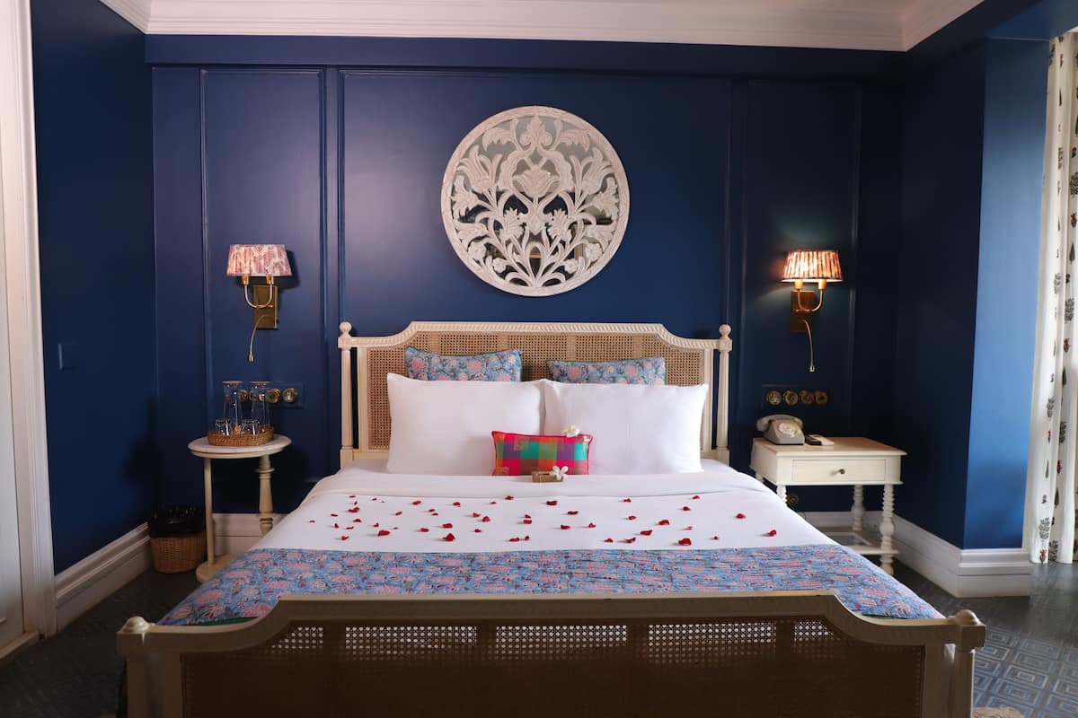 Un dormitorio con una cama grande, dos mesitas de noche, un adorno en la pared y una colcha estampada.