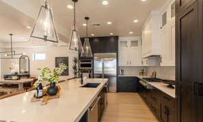 A modern kitchen with a central island, stainless steel appliances, and pendant lighting.