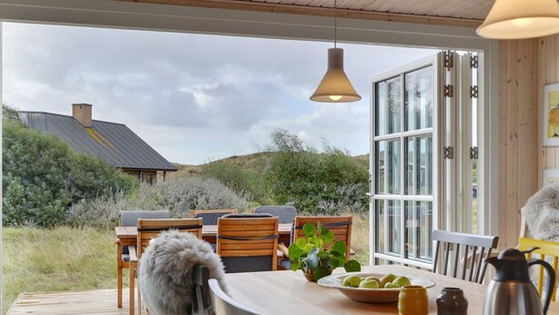 A wooden deck with outdoor seating, a table with a bowl of fruit, a cup, and a teapot. - "Urcu" - 475m from the sea by Interhome (Fanø)