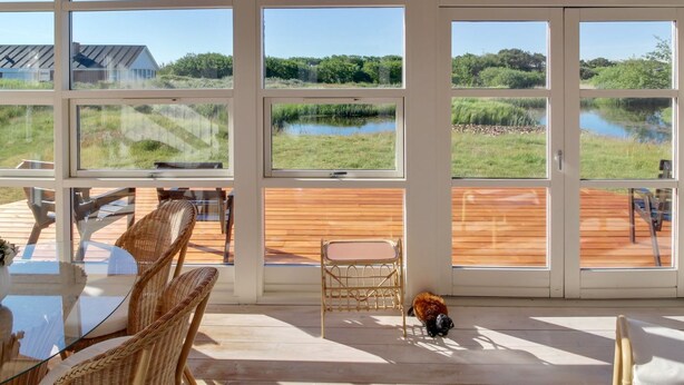 A covered outdoor area with large windows overlooking a lake and greenery. - "Allis" - 400m from the sea by Interhome (Fanø)