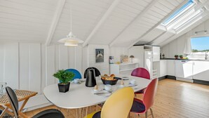 A bright, white interior with a round dining table, colorful chairs, and a skylight above. - "Maxie" - 1.2km from the sea by Interhome (Fanø)