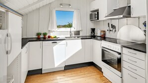 A modern kitchen with white cabinetry, a skylight, a window, and a view of the outdoors. - "Maxie" - 1.2km from the sea by Interhome (Fanø)