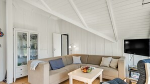A modern living room with a large L-shaped sofa, a small white table with a fruit bowl, a comfortable armchair, and a flat-screen TV mounted on the wall. - "Maxie" - 1.2km from the sea by Interhome (Fanø)