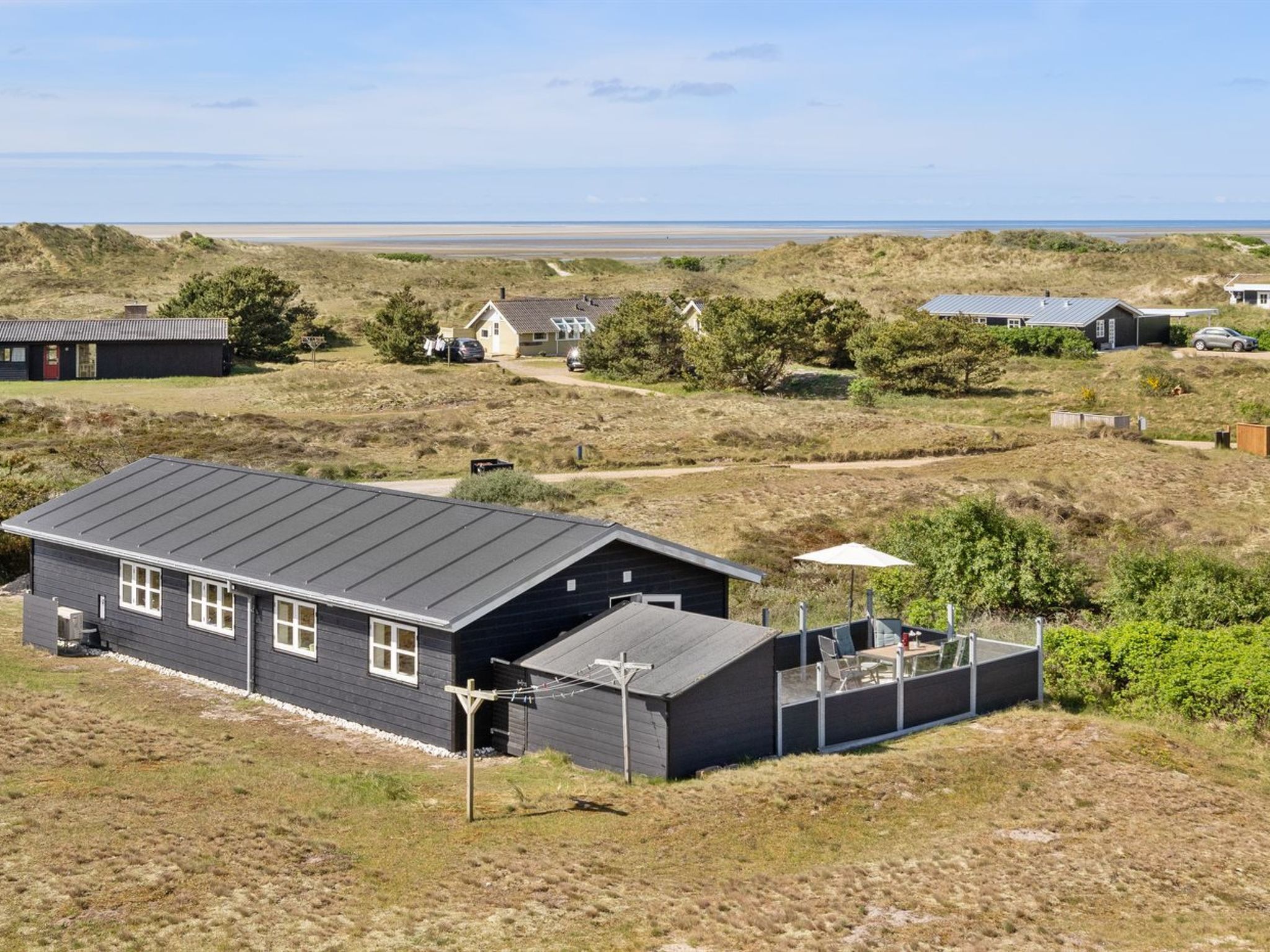 A modern house with a flat roof, a small attached garage, and a covered outdoor seating area.