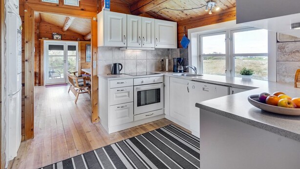 Una cocina moderna con armarios blancos, un ventanal y vistas al exterior.