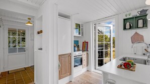 A modern kitchen with white cabinetry, a wooden floor, and a large window offering a view of the outdoors. - "Neija" - 800m from the sea by Interhome (Fanø)