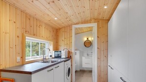 A compact kitchen with wooden walls, a built-in washing machine, and a window providing natural light. - "Stefana" - 200m from the sea by Interhome (Fanø)