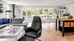 Ein modernes Wohnzimmer mit Kamin, Essbereich und großen Fenstern mit Blick ins Freie.
