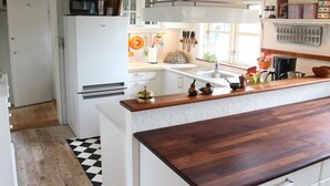 Une cuisine avec des meubles blancs, un plan de travail en bois et un sol à carreaux noirs et blancs.