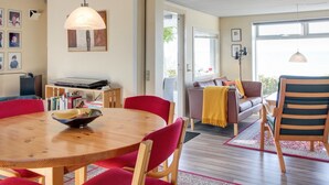 A modern living room with a wooden dining table, red chairs, a sofa, and a coffee table.