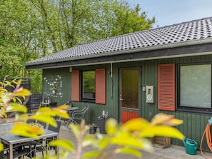 A building with a tiled roof, a door with a window, and a small outdoor seating area with tables and chairs.