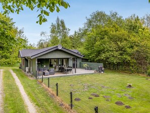A single-story building with a covered patio area, a dining table, and chairs.