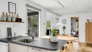 A modern kitchen with a large island, a dining area with a wooden table, and a cozy living space with a bed and a window. - "Nyalle" - 30km from the sea by Interhome (Toftlund)