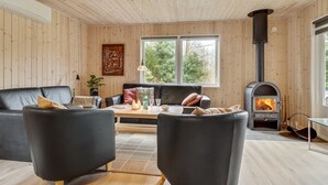 Una sala de estar acogedora con chimenea, paredes de madera y un ventanal grande.