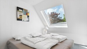 Quarto com cama, claraboia, pintura e abajur.
