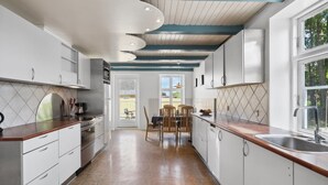 Cozinha moderna com armários brancos, bancada de madeira e painel de azulejos.