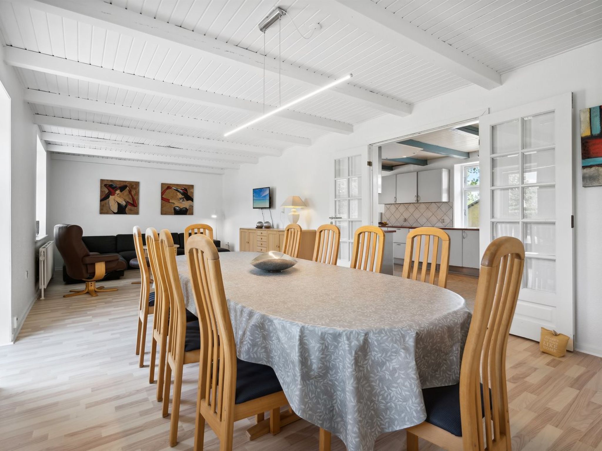 Un grand espace à manger avec une table ronde, des chaises en bois et, au fond, une cuisine moderne.