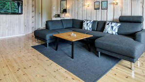 Een moderne woonkamer met een hoekbank, een houten salontafel en een groot raam.