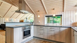 Een moderne keuken met houten kastjes, een roestvrijstalen oven en een groot raam met uitzicht op groen.