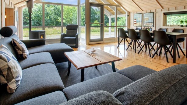 Een moderne woonkamer met een grote bank, een salontafel en een eethoek met stoelen en een tafel.