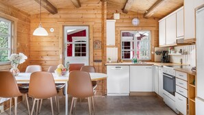 Ein Holzblockhaus im Inneren mit Essbereich, Küche und einem großen Fenster.