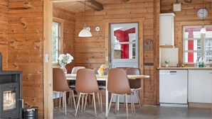 Ein Holzblockhaus-Interieur mit Essbereich, Küche und Kamin.