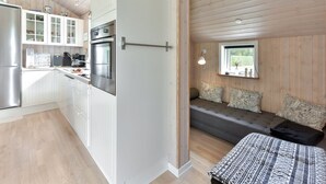 A modern kitchen with white cabinets, stainless steel appliances, and a dining area with a bench and cushions. - "Estrid" - 30km from the sea by Interhome (Toftlund)