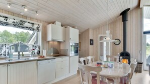 A modern kitchen with white cabinetry, a built-in oven, and a dining area with a round table and chairs. - "Estrid" - 30km from the sea by Interhome (Toftlund)