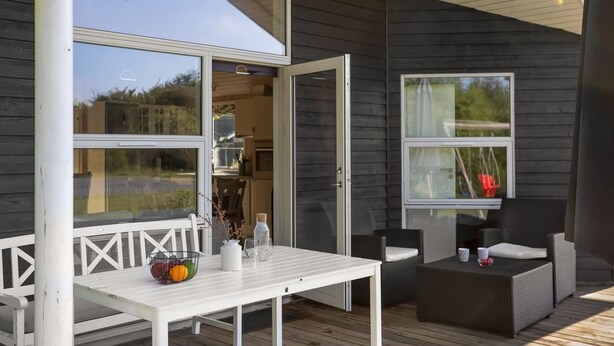 An outdoor deck with a white table, wicker furniture, and a view of the surrounding area. - "Estrid" - 30km from the sea by Interhome (Toftlund)