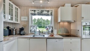 A modern kitchen with white cabinetry, a built-in oven, and a window with a floral curtain. - "Estrid" - 30km from the sea by Interhome (Toftlund)