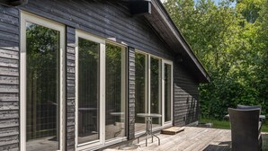 Een houten terras met een glazen deur, een kleine tafel en een stoel.