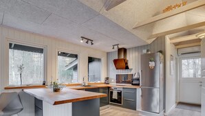 Een moderne keuken met een centraal eiland, inbouwapparatuur en grote ramen.
