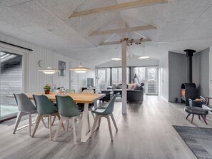 Uma sala de estar moderna com uma mesa de jantar de madeira, cadeiras verdes, um sofá e uma lareira.