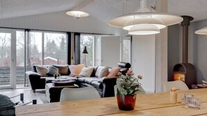Een moderne woonkamer met een houten eettafel, een bank en een groot raam.