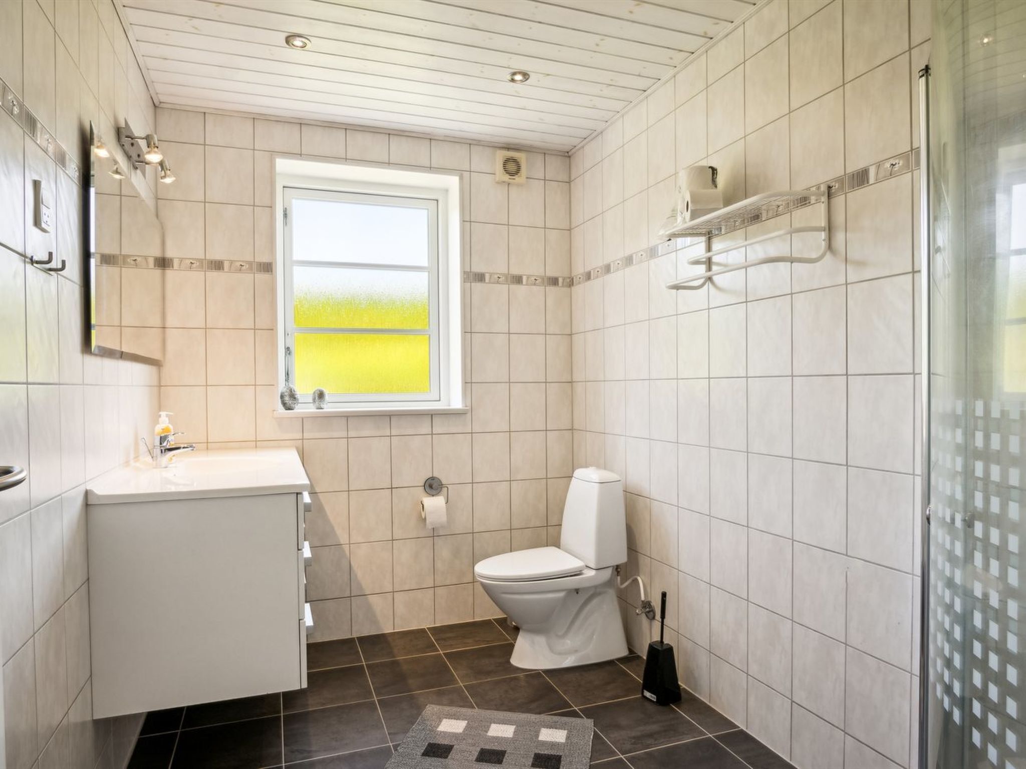 Une salle de bain avec des toilettes, un lavabo et une fenêtre.