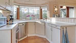 A modern kitchen with a large window, wooden ceiling, and a built-in oven.